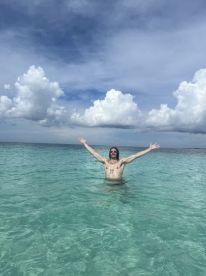 A man joyfully celebrates in the crystal-clear waters, showcasing the beauty of ocean adventures — perfect for summer getaways and beach fun.