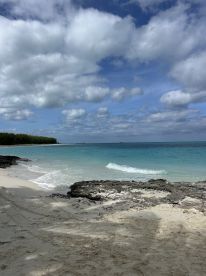 A scenic view of a beach with gentle waves and a cloudy sky, creating a tranquil atmosphere ideal for relaxation.