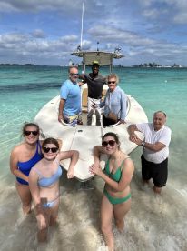 A joyful group poses by their boat on a beautiful beach, enjoying a fun day in the water — perfect for family outings and beach adventures.