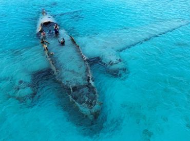 A group of snorkelers explores a sunken wreck in crystal-clear waters, showcasing an adventurous underwater experience perfect for marine enthusiasts.