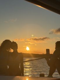 A group of friends captures a beautiful sunset while enjoying their time on a boat, creating unforgettable memories against a stunning backdrop.