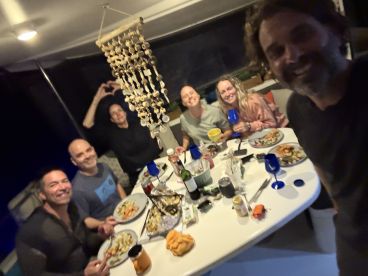 A joyful group enjoys a festive dinner aboard a boat, showcasing delicious food and drinks in a cozy setting — perfect for memorable gatherings on the water.