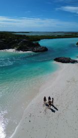 A group of friends enjoys a beautiful beach day on a secluded shore, surrounded by stunning turquoise waters — perfect for relaxation and adventure.