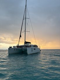 A serene view of a catamaran anchored in calm waters at sunset, showcasing the vessel's elegant lines against a colorful sky.