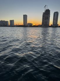 A stunning sunset over a city skyline, reflecting beautifully on the water — a perfect backdrop for evening boat cruises.