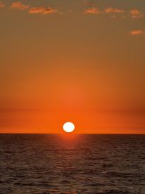 A breathtaking sunset over the ocean, casting vibrant orange hues across the water — a perfect backdrop for romantic evenings or serene boat trips.