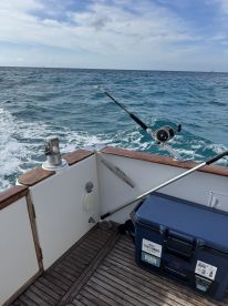 A well-equipped fishing area on a boat featuring a cooler and fishing gear, perfect for a day out on the water.