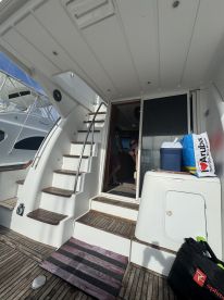 A glimpse into the interior of a yacht, showcasing the cabin area with seating and steps leading to the helm, perfect for relaxing or navigating the waters.