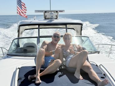 A cheerful couple enjoys a sunny day on the boat, giving thumbs up as they cruise through the water — perfect for memorable boating adventures.