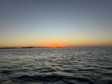 A blurry image capturing a sunset over the water, lacking clarity and detail.