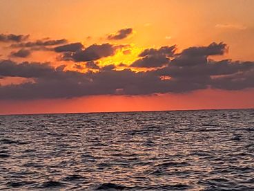 A stunning sunset over the ocean, creating a picturesque backdrop perfect for evening boat cruises.