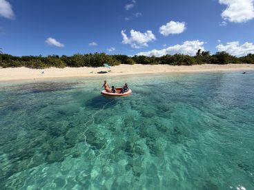 A group enjoys a fun day on an inflatable boat in crystal-clear waters, perfect for beach adventures and family outings.