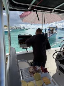 A chef prepares food on a grill aboard a boat, showcasing the onboard catering amenities perfect for a day on the water.