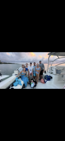 A joyful group of friends and family gather on a boat, capturing a memorable moment together against a beautiful sunset backdrop.