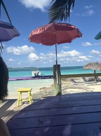 A picturesque beach scene featuring colorful umbrellas and a boat anchored in the clear turquoise waters, perfect for a relaxing day by the shore.