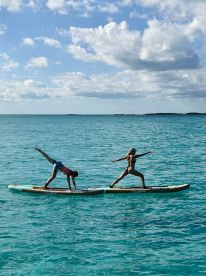 Two friends showcase their paddleboarding skills in crystal-clear waters, making for a fun and adventurous day on the water.