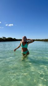 A woman enjoys a refreshing swim in crystal-clear waters, surrounded by lush greenery — a perfect moment for beach lovers and adventure seekers.