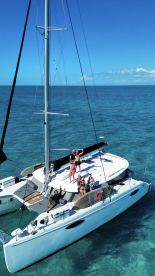 A lively group enjoys a day on a catamaran, celebrating under the sun with clear turquoise waters surrounding them — the perfect backdrop for unforgettable memories.