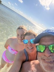 A joyful family selfie in shallow waters, capturing a fun day at the beach — perfect for family vacations and memorable moments in the sun.