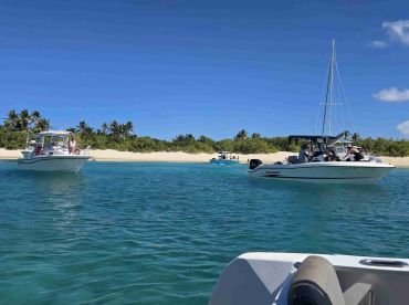 A vibrant scene featuring multiple boats anchored near a beautiful beach, perfect for a sandbar stop and group fun in the sun.