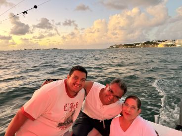 A joyful group enjoys a sunset cruise, capturing the essence of celebration on the water with picturesque views in the background.