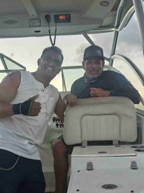 Two men pose inside the helm area of a boat, showcasing the comfortable seating and control panel — perfect for navigating adventures on the water.