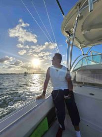 A man enjoys the sunset while leaning against the side of a boat, capturing the essence of a relaxing day on the water.