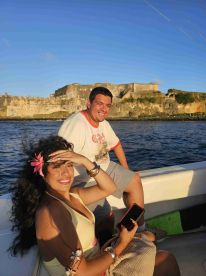 A joyful couple enjoys a boat ride with a historic landmark in the background, capturing the essence of adventure and relaxation on the water.