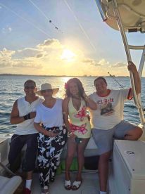 A joyful group of friends poses for a photo on a boat at sunset, capturing the essence of a perfect day on the water.