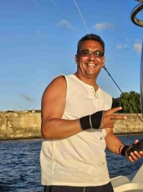 A smiling man poses on a boat, showcasing a joyful moment on the water — perfect for capturing the spirit of a fun day out at sea.