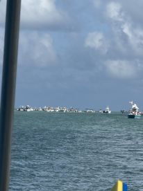 A lively scene at a popular sandbar with multiple boats gathered, showcasing the vibrant atmosphere of a day on the water.