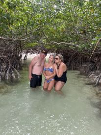 A fun group poses together while wading in shallow water surrounded by mangroves, capturing a memorable moment during their aquatic adventure.