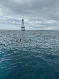 A group of snorkelers enjoys the ocean near a historic lighthouse, creating a memorable underwater adventure in a stunning marine environment.