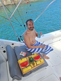 A man enjoys a refreshing assortment of fruits and snacks aboard a boat, perfect for a relaxing day on the water.