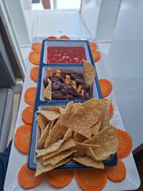 A beautifully arranged platter of snacks featuring chips, salsa, and chocolate treats, perfect for enjoying on a boat trip.