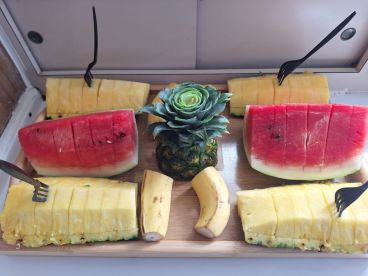 A vibrant display of fresh fruit including watermelon, pineapple, and bananas, perfect for enjoying on a boat trip or as a refreshing snack.