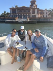 A cheerful group enjoys a day on the water aboard a boat, with a stunning historic building in the background — perfect for memorable outings and celebrations.