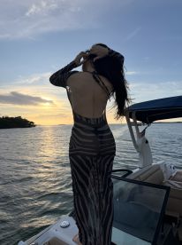 A woman poses gracefully on the deck of a boat during a stunning sunset, capturing the essence of a perfect evening on the water.