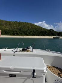 A clear view of a boat's deck with a YETI cooler, showcasing the serene waters and lush green hills in the background — perfect for a day out on the water.