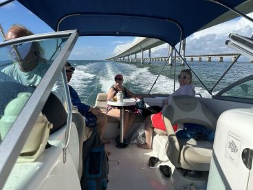 A lively group enjoys a day on the water aboard a boat, with scenic views and camaraderie as they cruise under a bridge.