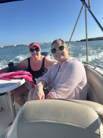 Two friends enjoy a sunny day on the water, smiling and relaxing on a boat — perfect for creating unforgettable memories on a boating adventure.