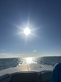 A scenic view from the bow of a boat, capturing the sun shining over the ocean — perfect for enjoying a day on the water.