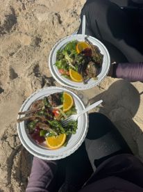 Two plates of delicious grilled lamb chops and fresh salad served on the beach, perfect for a relaxing day by the water.