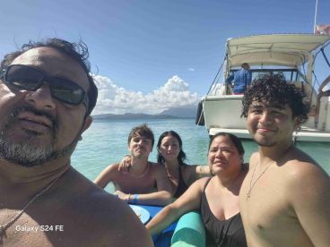 A joyful family enjoys a day in the water, capturing memories with a boat in the background — perfect for summer adventures and family bonding.