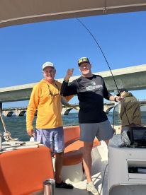 Two anglers celebrate a successful catch aboard a boat, showcasing the joy of fishing trips with friends.