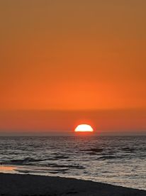 A stunning sunset over the ocean, creating a vibrant orange sky — perfect for romantic evenings or serene moments by the water.