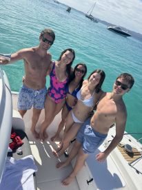 A cheerful group of friends poses on the deck of a boat, enjoying a sunny day on the water — perfect for family outings or fun adventures at sea.