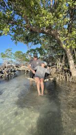 A couple enjoys a playful moment on a swing in shallow water surrounded by mangroves, capturing the essence of adventure and fun in nature.