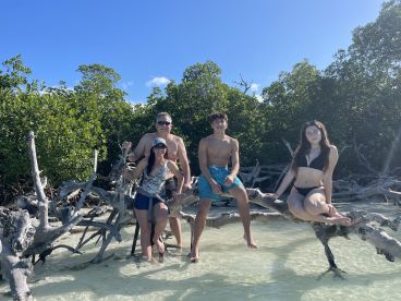 A cheerful group enjoys a sunny day at a mangrove beach, posing playfully in the shallow water — perfect for family adventures and nature exploration.