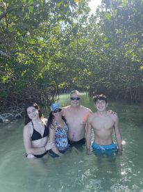 A joyful family enjoys a refreshing swim in the mangroves, capturing a perfect moment of togetherness and adventure in nature.